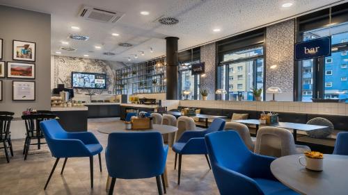 a restaurant with blue chairs and tables and a bar at Holiday Inn - the niu, Square Mannheim by IHG in Mannheim