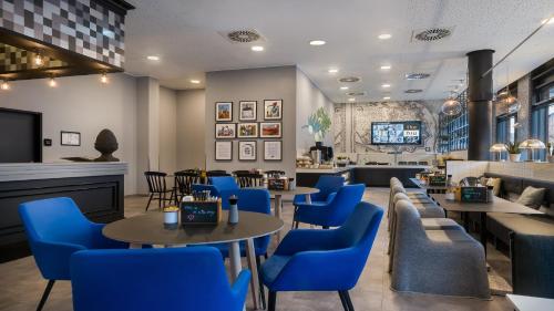 a waiting room with blue chairs and tables at Holiday Inn - the niu, Square Mannheim by IHG in Mannheim