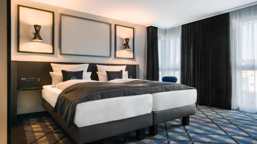 a bedroom with a large bed in a room with windows at Holiday Inn - the niu, Square Mannheim by IHG in Mannheim