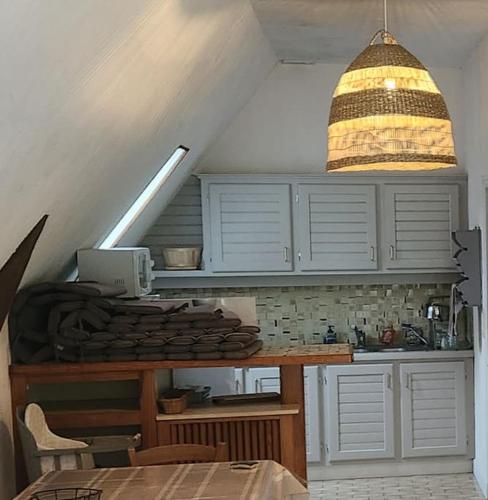 une cuisine avec des placards blancs et une lampe pendant dans l'établissement Villa La Cayrouse Piscine Tennis Boulodrome, à Le Bouyssou