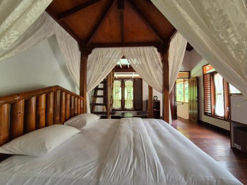 a bedroom with a large white bed with a canopy at Sam's Bungalows And Treks in Bukit Lawang