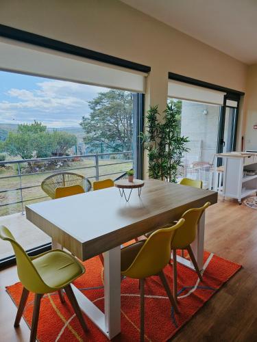 a dining room with a table and chairs and a large window at Junção - Apartamentos Completos in Miranda do Douro