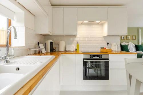 a white kitchen with white cabinets and a sink at Stylish country apartment near Rookery Hall in Worleston