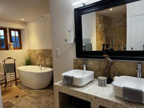 a bathroom with two sinks and a large mirror at demeure de luxe, piscine sauna billard pétanque in Yèvre-le-Châtel