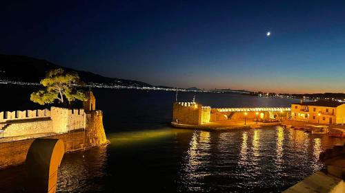 a castle on the water at night with the moon at Nostos Luxury Villas with Private Pool in Nafpaktos in Nafpaktos