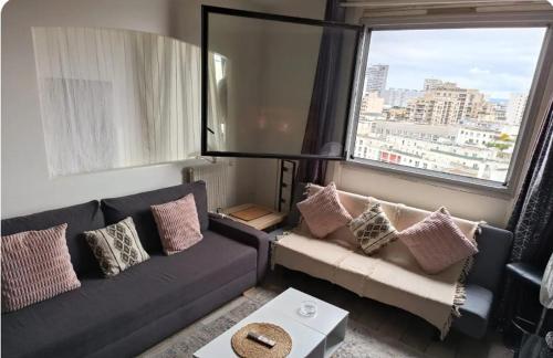 un salon avec un canapé et une fenêtre dans l'établissement Grand appartement proche métro quartier la defense, à Courbevoie