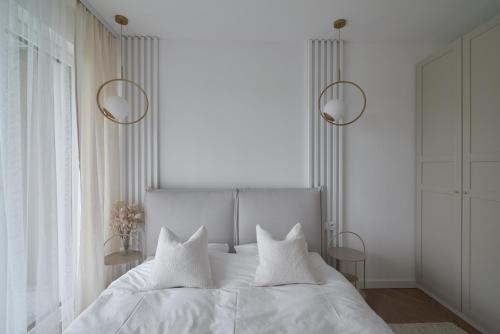 a white bedroom with a white bed with two pillows at Apartament Sienkiewicza 22B in Zamość