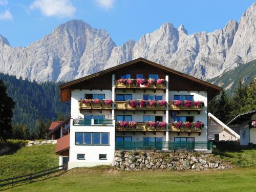 a building with flowers on the balconies in front of mountains at Aparthotel Sunrise in Ramsau am Dachstein