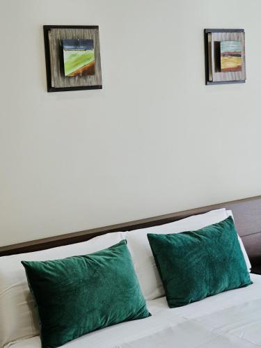 a white bed with two green pillows on it at Junção - Apartamentos Completos in Miranda do Douro