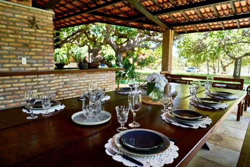 a wooden table with plates and wine glasses on it at Casa Barra Nova in Cascavel
