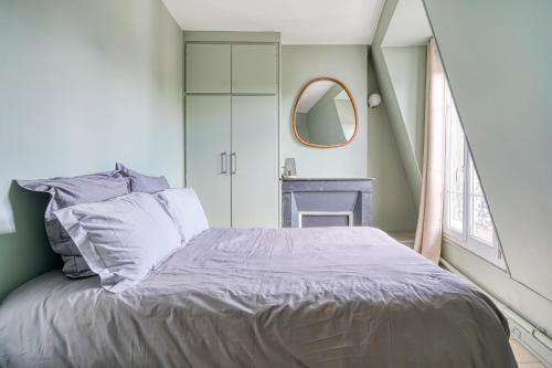 - une chambre avec un lit et un miroir rond dans l'établissement F2 Parisien - Père Lachaise, à Paris