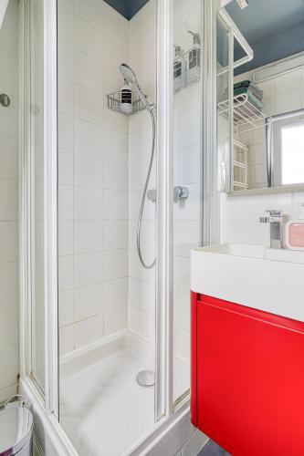 La salle de bains est pourvue d'une armoire rouge et d'une douche. dans l'établissement F2 Parisien - Père Lachaise, à Paris