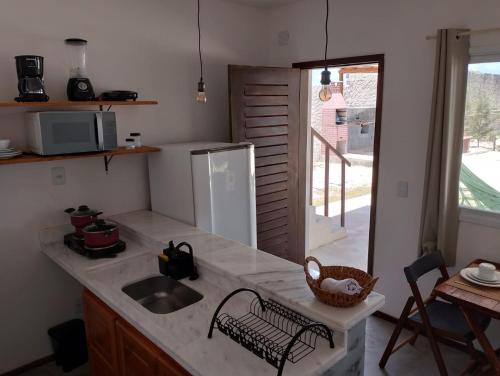 a kitchen with a counter with a sink and a refrigerator at Ventos de sibaúma in Sibauma