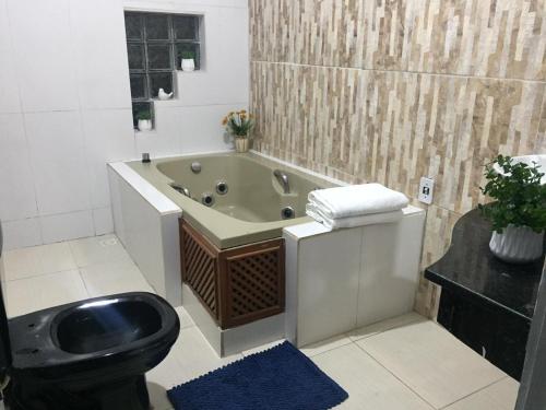 a bathroom with a bath tub and a toilet at Zaffir Apartamento in Várzea Grande