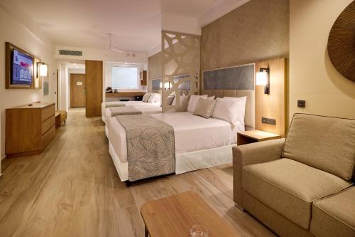 a large hotel room with a bed and a couch at Riu Palace Bavaro - All Inclusive in Punta Cana