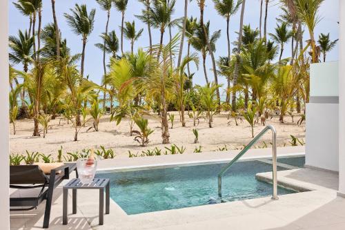 a swimming pool with palm trees and a beach at Riu Palace Bavaro - All Inclusive in Punta Cana