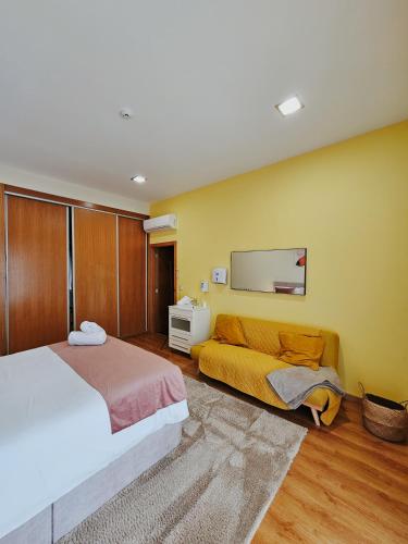 a bedroom with a bed and a couch and a mirror at Junção - Apartamentos Completos in Miranda do Douro