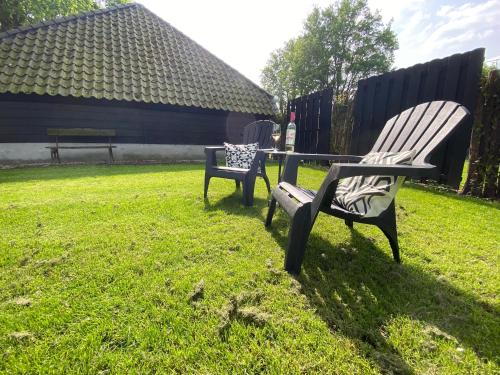 two benches sitting in the grass in a yard at Antoniushofke in Asten