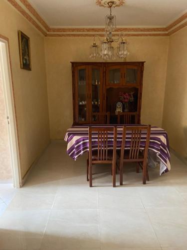 a dining room table with two chairs and a chandelier at Appartement Belevédère in Casablanca