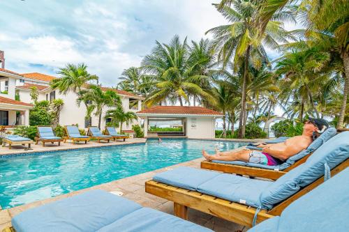 a man laying on a beach chair next to a swimming pool at Tradewinds Paradise Villas in San Pedro