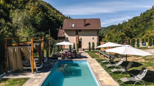 a pool with chairs and umbrellas in front of a house at Zeleni svet 2 in Crni Vrh