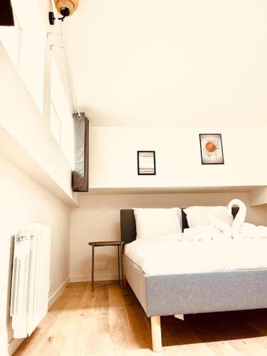 Cette chambre blanche dispose d'un lit et d'un escalier. dans l'établissement Stylish Loft Paris 17- 3 bdrs - 2 bathrs - 7 pers, à Paris