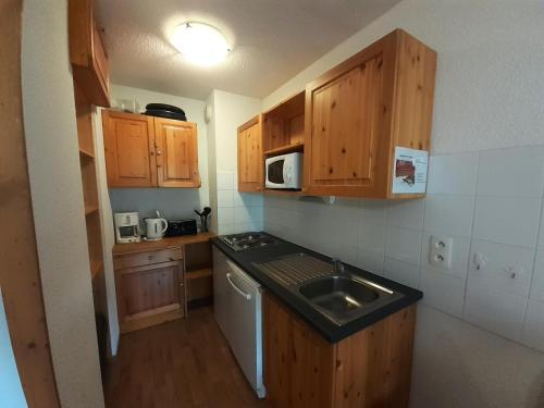 Elle comprend une petite cuisine avec des placards en bois et un évier. dans l'établissement Chalet Florence - Studio pour 4 Personnes MAE-0371, à Modane