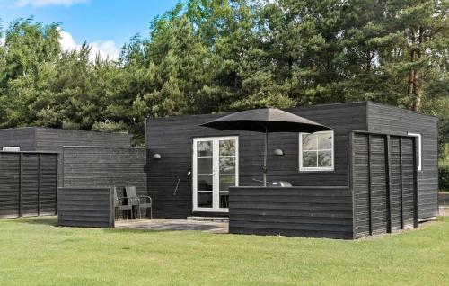 a black cabin with an umbrella in the grass at Nice Apartment In Væggerløse With Wifi in Marielyst