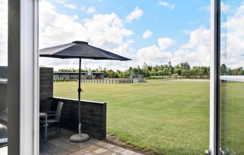 a patio with an umbrella and a grass field at Nice Apartment In Væggerløse With Wifi in Marielyst