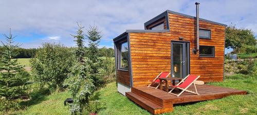 a tiny house with two chairs on a deck at Tiny House Pod Třešní in Kaznějov