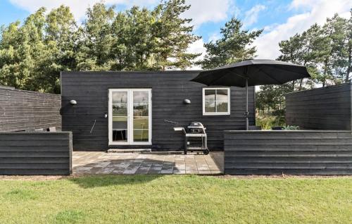 a black tiny house with a chair and an umbrella at 2 Bedroom Nice Apartment In Væggerløse in Marielyst