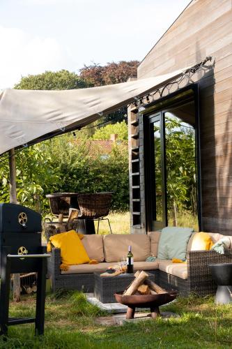 a couch sitting under a tent in the grass at Tiny House Stijl & natuur nabij Brugge! in Beernem