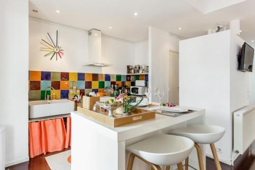 une cuisine avec un évier et un comptoir avec des tabourets dans l'établissement Flat Seventies and terrace - Welkeys, à Marseille