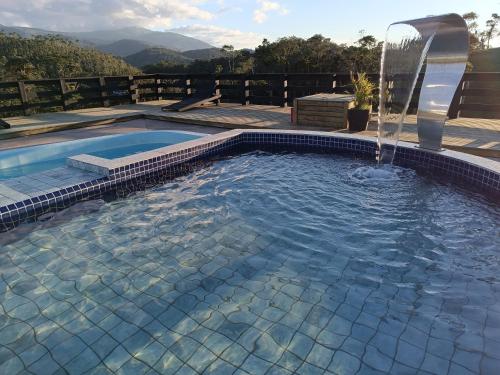 ein Swimmingpool mit Wasserfontäne in der Unterkunft Chalés Refúgio nas montanhas in Guaratuba