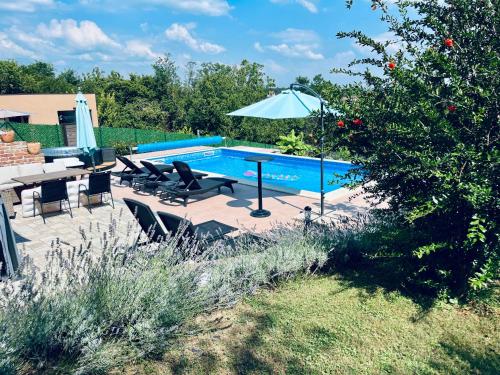 a swimming pool with a table and an umbrella at Harmony in Kapela