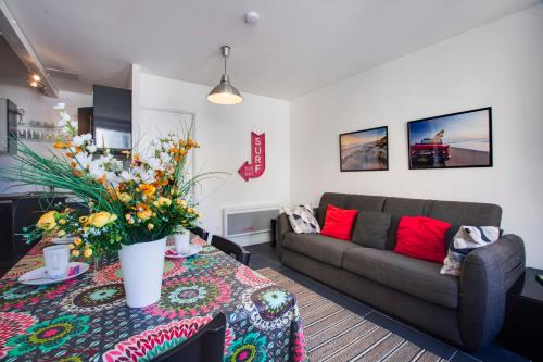 a living room with a couch and a table with flowers at Appartement Mazagran - Welkeys in Biarritz