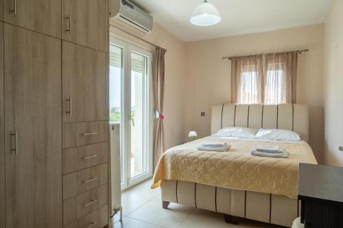 a bedroom with a bed and a large window at Palaiologou Panorama Apartments in Mantamádos
