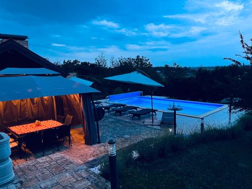 a pool with a table and umbrellas at night at Harmony in Kapela