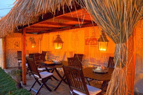 a patio with a table and chairs under a thatch roof at ZEVKLİLER ALAÇATI hotel in Alacati