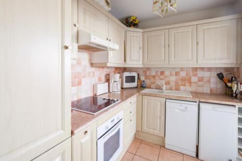 une cuisine avec des armoires blanches et des appareils électroménagers blancs dans l'établissement Appartement Lanterne Welkeys, à Nice