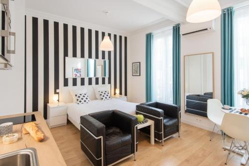 une chambre avec un lit blanc et deux chaises dans l'établissement Le Studio Graphite Welkeys, à Nice