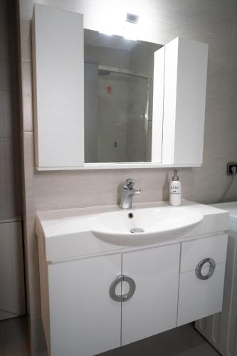 a bathroom with a white sink and a mirror at Palaiologou Panorama Apartments in Mantamádos
