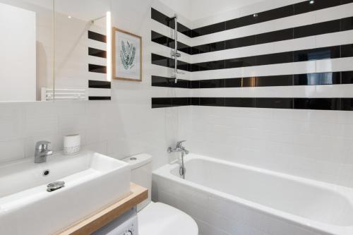 La salle de bains est pourvue d'une baignoire blanche, de toilettes et d'un lavabo. dans l'établissement Le Studio Graphite Welkeys, à Nice