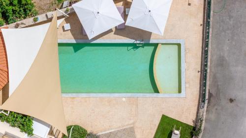 an overhead view of a swimming pool with umbrellas at Palaiologou Panorama Apartments in Mantamádos
