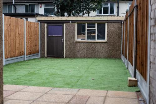 Un patio vacío con una valla y un garaje. en TLM Stays 3-Bed Entire Home, en Dagenham