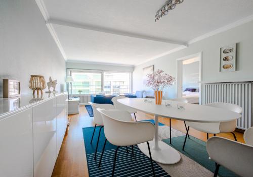 a kitchen and living room with a white table and chairs at Zeezicht Oostduinkerke - Amu-ZEE-Vous in Oostduinkerke