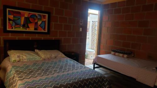 a bedroom with a bed and a brick wall at Hospedaje rural y restaurante in Santa Rosa de Cabal