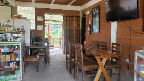 a dining room with a table and chairs and a television at Hospedaje rural y restaurante in Santa Rosa de Cabal