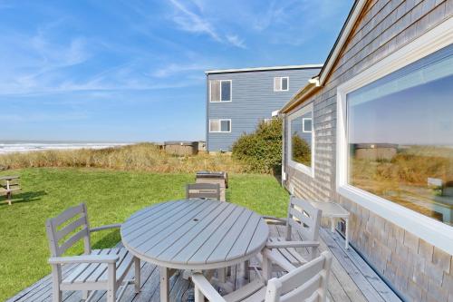 a table and chairs on a deck with a view of the ocean at Breakers Cottage in Rockaway Beach