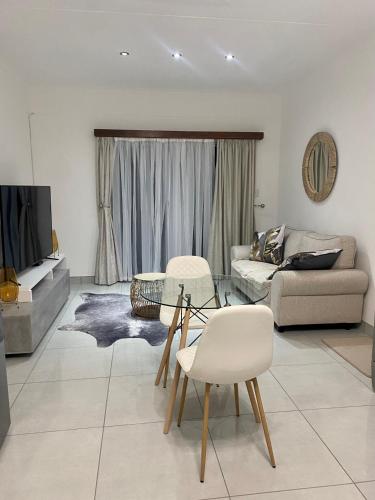 a living room with a couch and a table and chairs at Zahara Cousy Home in Windhoek